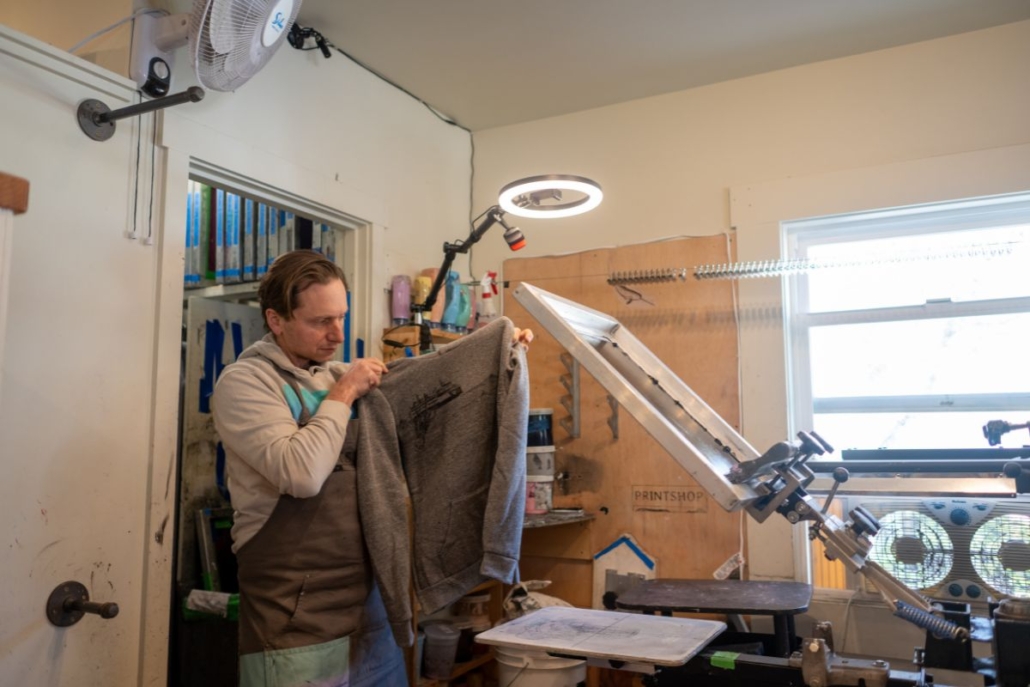 Andrew Youngren holding up a printed sweatshirt