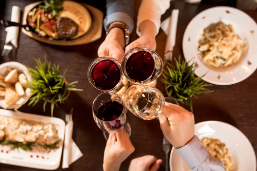 Close up shot of unrecognizable group of friends cheering with red wine